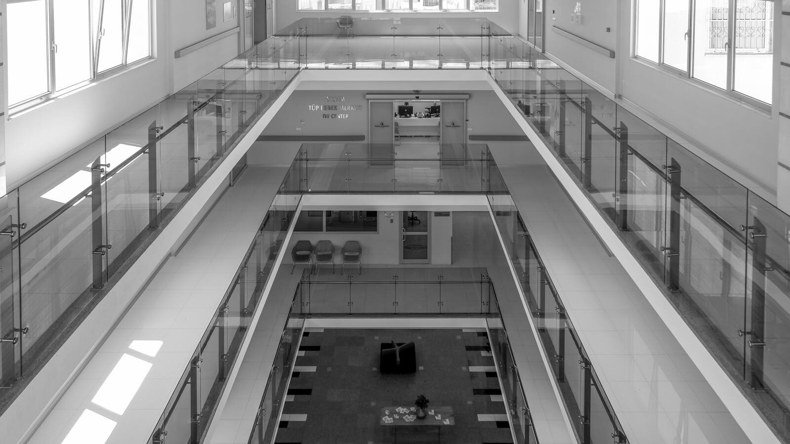 Spacious modern office interior featuring sleek glass balustrades and symmetrical architecture in black and white.